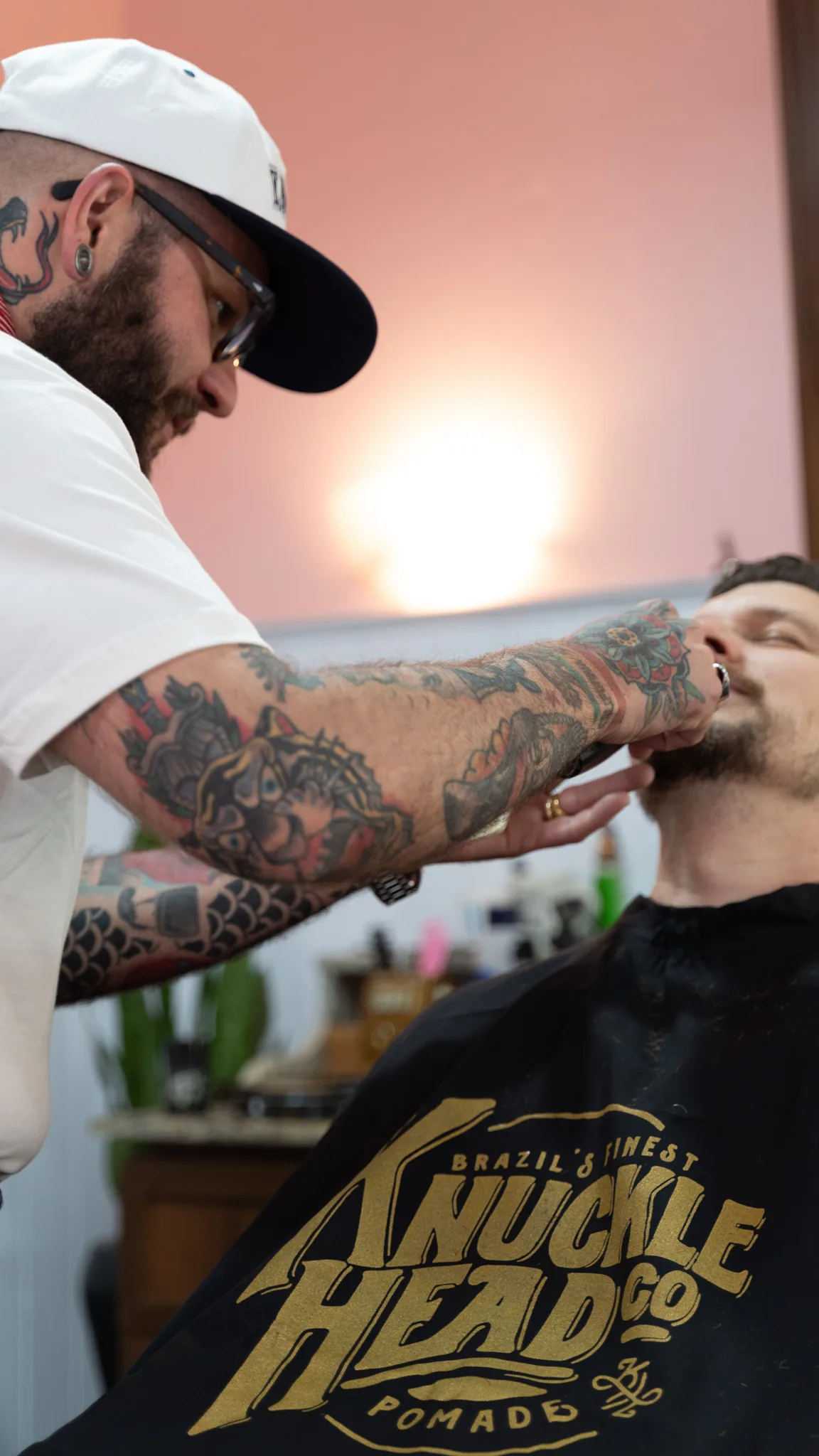 Barbeiro finalizando a barba com a capa de atendimento Knucklehead